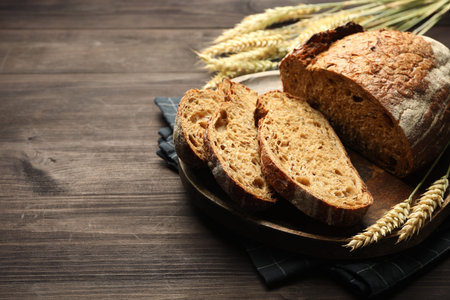 Pieces of fresh bread and spikes on wooden table, closeup. Space for text