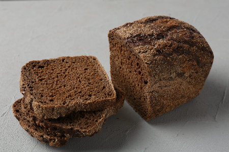 Pieces of fresh rye bread on light gray textured table, closeup