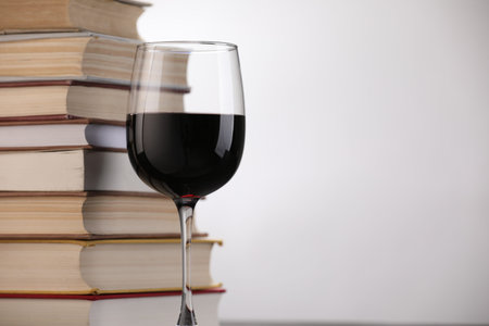Red wine in glass and stack of books on light background, closeup. Space for textの写真素材