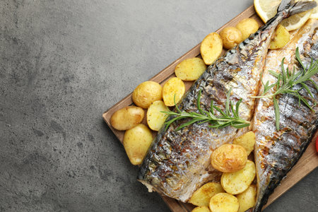 Homemade seafood dish. Tasty roasted mackerels with spices and vegetables on gray table, top view. Space for textの写真素材