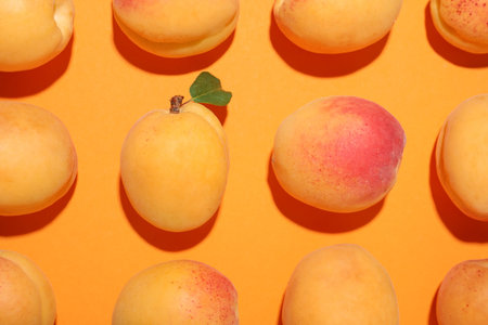 Fresh ripe apricots on orange background, flat lay