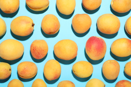 Fresh ripe apricots on light blue background, flat lay