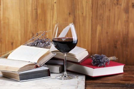 Red wine in glass, lavender flowers and books on wooden table, closeupの写真素材