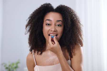 Beautiful Brazilian woman taking collagen pill indoorsの写真素材