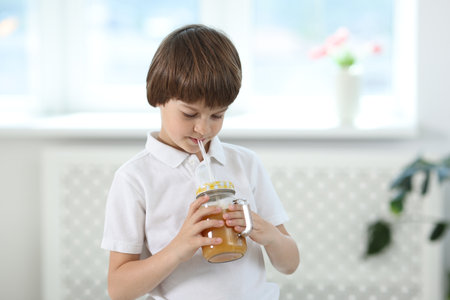 Cute little boy drinking orange juice at home. Refreshing drinkの写真素材