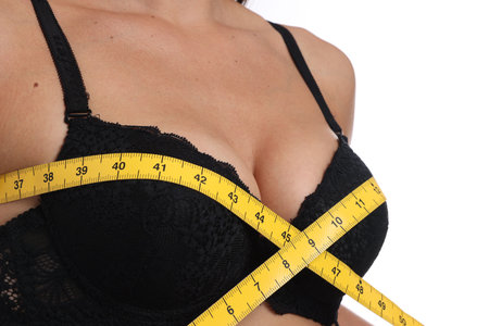 Woman in beautiful bra measuring breast circumference on white background, closeupのeditorial素材