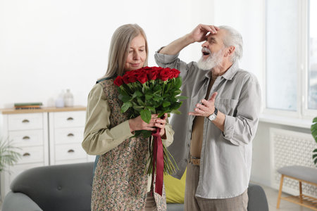 Cute couple with bouquet of red roses at homeの写真素材