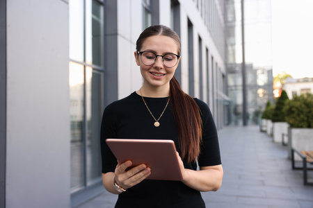 Successful businesswoman with tablet near office buildingの写真素材