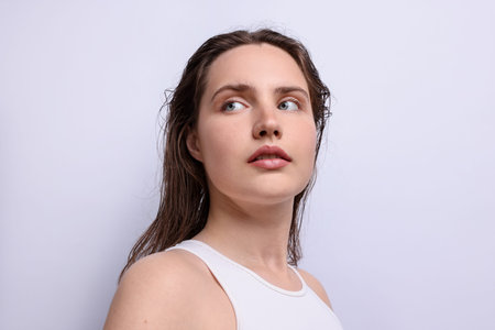 Beautiful woman with natural skin complexion on light grey background, closeup