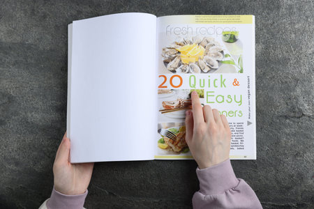 Woman reading magazine at gray table, top view. Mockup for designのeditorial素材
