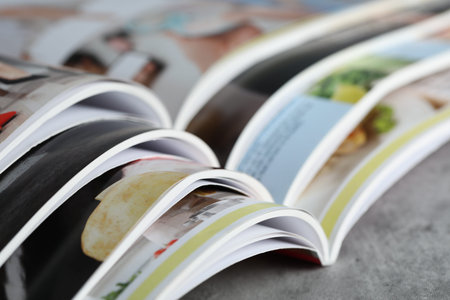 Different open magazines on gray table, closeup