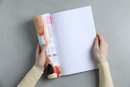 Woman reading magazine at light gray table, top view. Mockup for designの写真素材