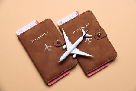 Airplane model, passports and flight tickets on beige background, flat lay
