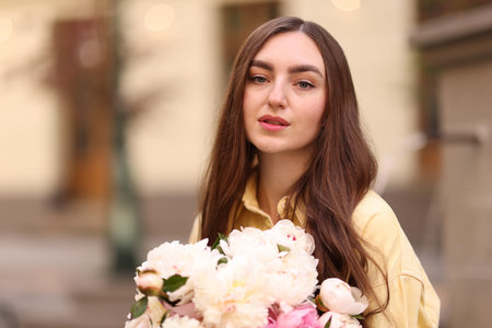 Woman with bouquet of beautiful peonies on city street. Space for textの写真素材