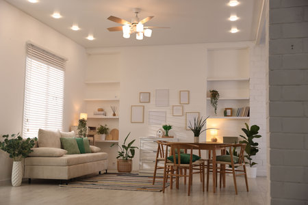 Stylish dining table with chairs and comfortable sofa in room. Interior design