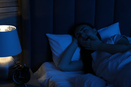Frustrated woman suffering from insomnia in bed at home