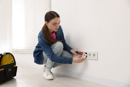 Woman with screwdriver installing new socket at home
