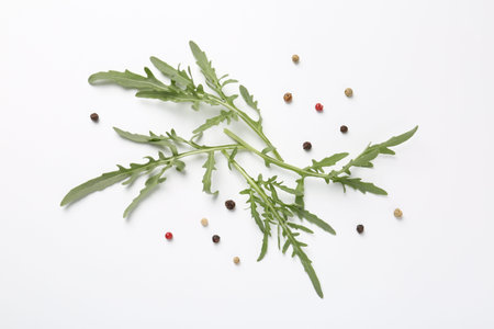 Fresh ripe green arugula leaves and peppercorns on white background, flat lay