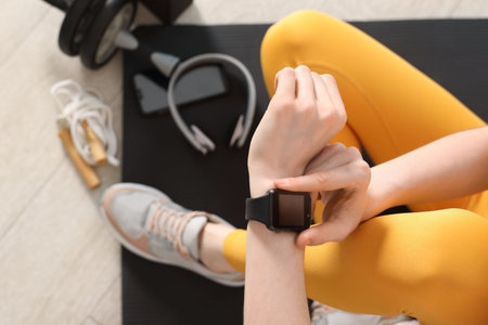 Woman checking fitness tracker during training indoors, closeupのeditorial素材
