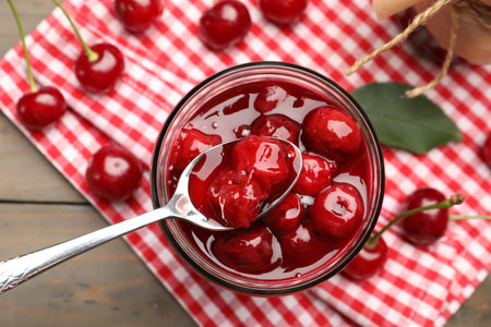 Tasty cherry jam and fresh fruits on wooden table, flat layの写真素材