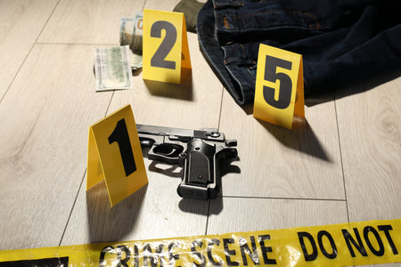 Forensic expertise. Crime scene with evidence, markers and police tape on floor, closeup