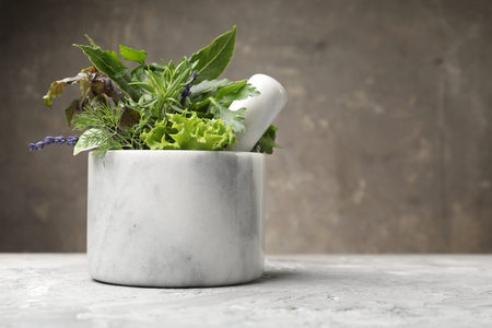 Mortar with pestle and different aromatic herbs on grey table, space for textの写真素材