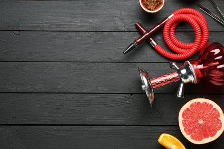 Hookah and fresh fruits on black wooden table, flat lay. Space for text