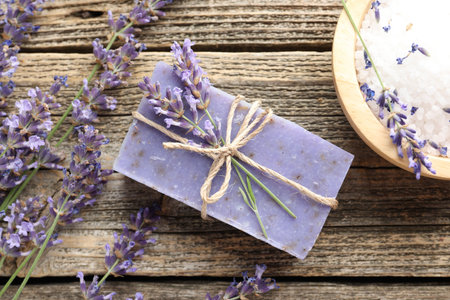 Aromatic soap bar, lavender flowers and sea salt on wooden table, flat layの写真素材