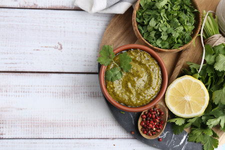 Tasty sauce with cilantro and other ingredients on white wooden table, top view. Space for text