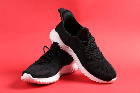 Pair of black sneakers on red background