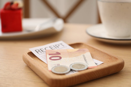 Tips and receipt on wooden table in restaurant, closeup. Gratuity for workの写真素材