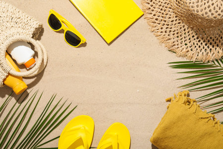 Flat lay composition with different beach accessories and palm leaves on sand outdoors, space for...