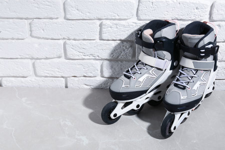 Pair of roller skates on gray marble table near white brick wall, above view. Space for text