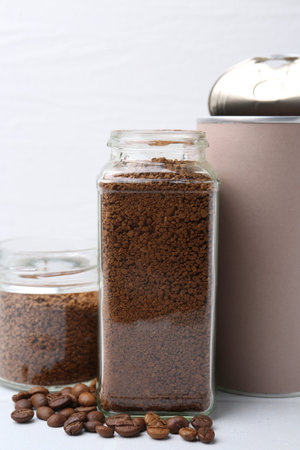 Instant coffee in jars and beans on white tiled table, closeupの写真素材
