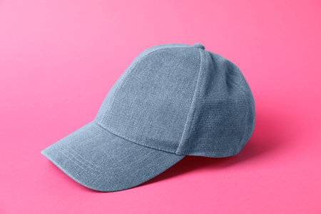 Denim baseball hat on pink background, closeup