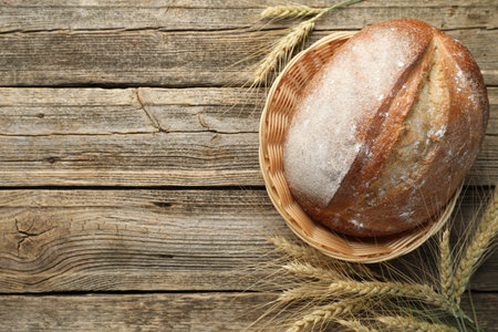 Loaf of fresh bread and spikes on wooden table, flat lay. Space for textの写真素材
