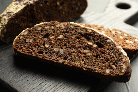 Pieces of fresh rye bread with seeds on table, closeup
