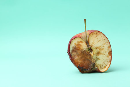 Half of spoiled apple on turquoise background. Space for text
