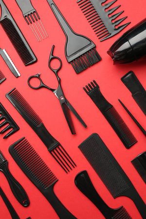 Different hairdresser's tools on red background, flat lay