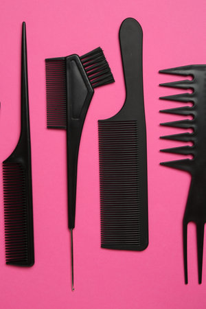 Different hairdresser's tools on pink background, flat lay