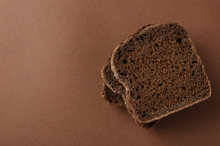 Pieces of fresh rye bread on brown background, top view. Space for text