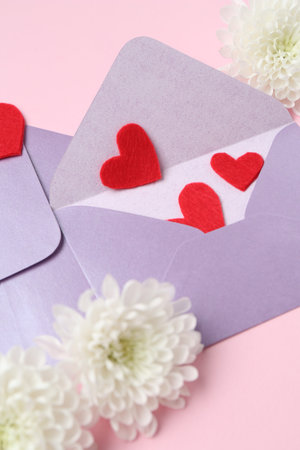 Love letters, flowers and red hearts on pink background, above view