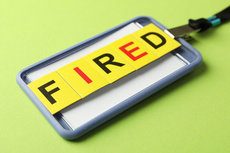 Dismissal. Word fired and badge on green background, closeup