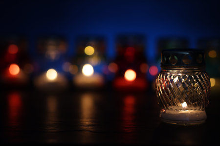 Many grave candles on black table against blue background, closeup