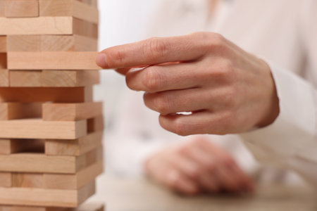 Lviv, Ukraine - December 21, 2023: Woman playing Jenga tower on blurred background, closeup