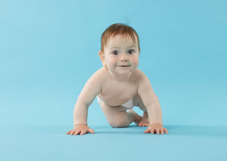 Cute little baby crawling on light blue background