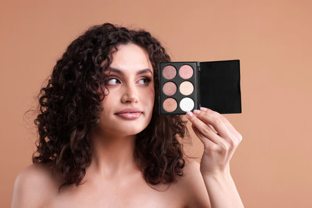 Woman with eyeshadow palette on beige background