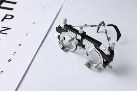 Trial frame and vision test chart on white background, closeup