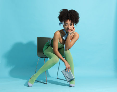 Fashionable portrait of beautiful Brazilian woman in stylish outfit on light blue background