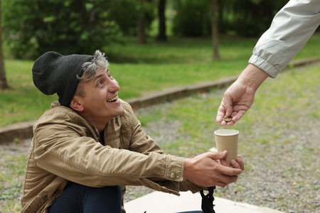 Man giving money to homeless person outdoors, closeup